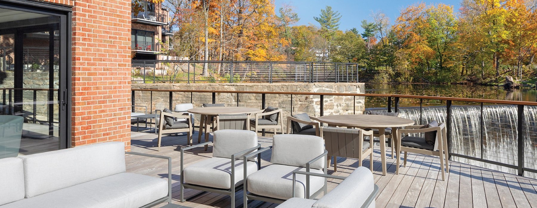a deck with tables and chairs on it and trees in the back